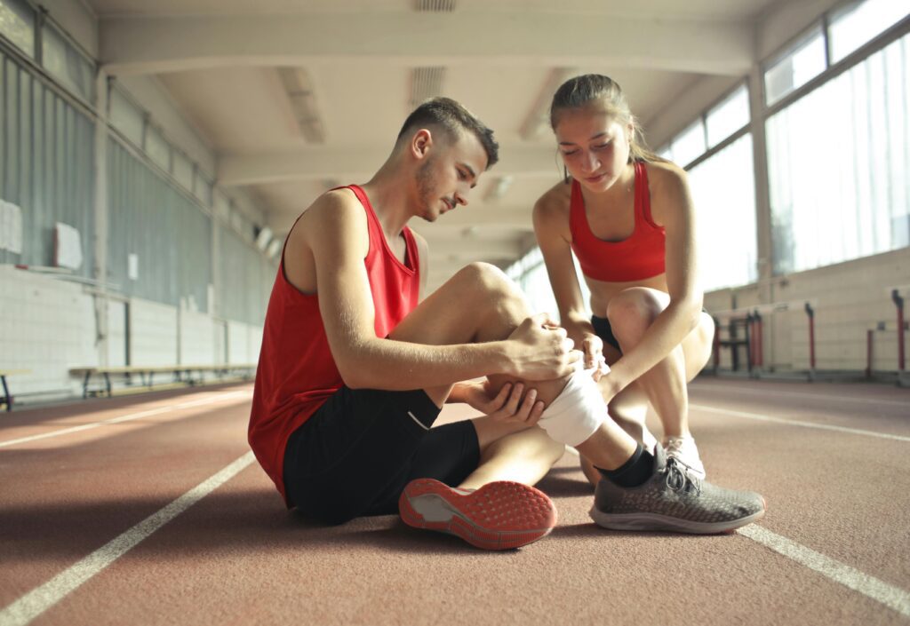 Dois atletas de atletismo, unidos pela amizade e espírito de equipe, se ajudam após um dos atletas sofrer uma lesão na perna. Enquanto um faz o curativo, o outro demonstra apoio, ajudando a superar o desafio da lesão e mostrando que, no esporte, a superação também passa pela solidariedade e apoio mútuo.