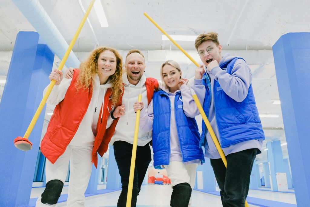 Time de curling comemorando após um jogo, mostrando a felicidade e construído através de um intenso trabalho em conjunto.