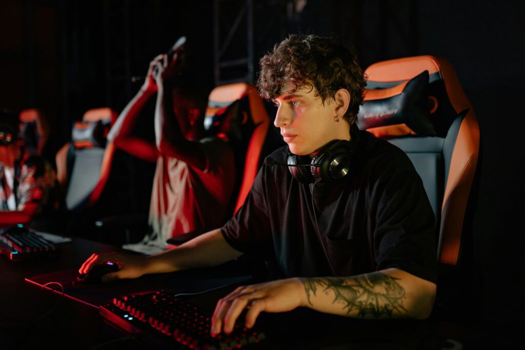 Jogador de eSports concentrado na tela, sentado na cadeira, enquanto se prepara ao lado de seu time para iniciar uma partida.