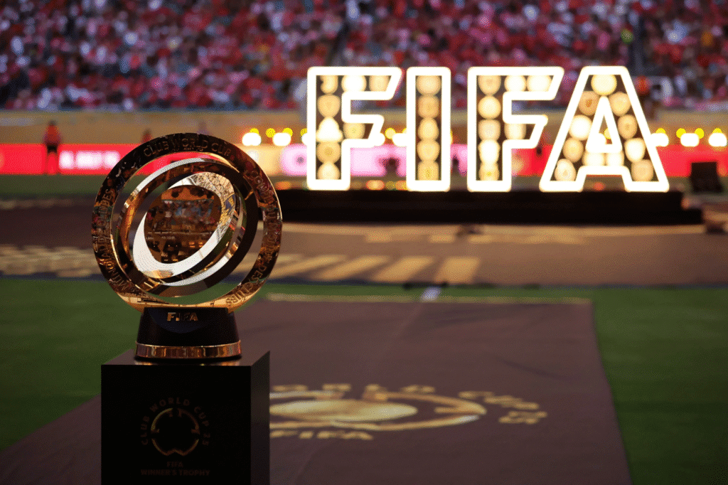 Estátua do troféu da FIFA Mundial de Clubes posicionada no centro do estádio, durante a cerimônia de abertura, com o gramado preparado e a torcida presente nas arquibancadas.
