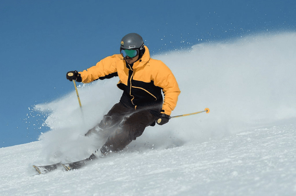 Atleta de ski descendo uma pista, equipado e totalmente concentrado, ciente de que qualquer erro pode impactar diretamente sua performance e alterar completamente seu resultado na competição.