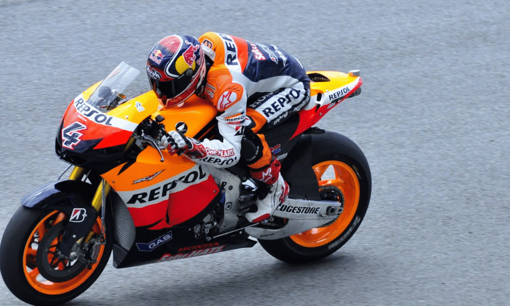Atleta de motovelocidade, totalmente equipado, faz uma curva com máxima concentração, sabendo que foco e precisão são fundamentais para sua performance e resultado na prova.