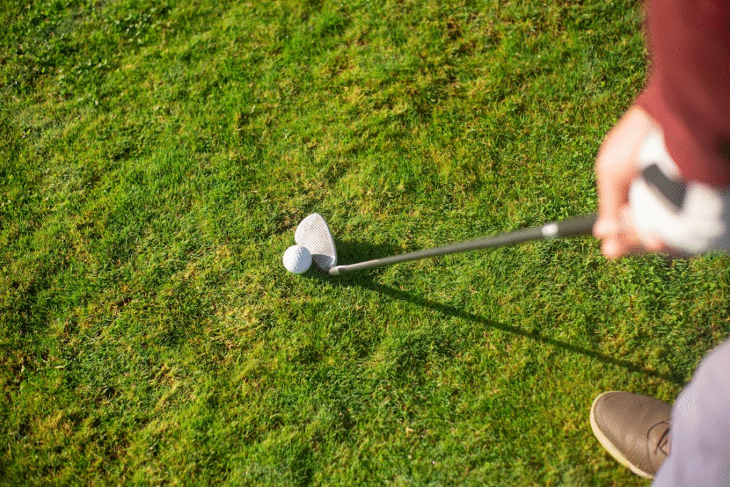 Golfista em posição de concentração total, com o taco alinhado e a bola centralizada, pronto para realizar o movimento de swing com precisão e força. A imagem destaca o momento decisivo do golpe no golfe, combinando técnica, foco mental e performance esportiva.