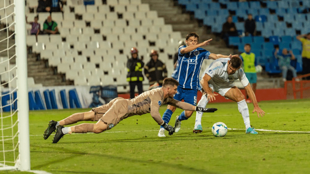 Um goleiro salta para defender a bola dentro da pequena área, enquanto o zagueiro tenta proteger e o atacante pressiona. A cena capta a tensão, o instinto e o medo de errar — elementos mentais que definem o desempenho sob pressão.