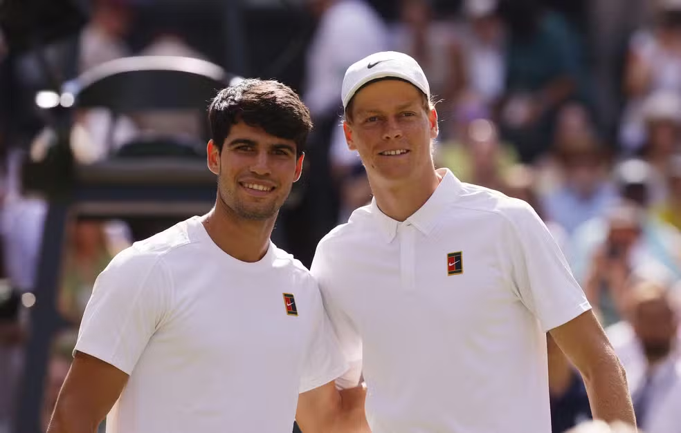 Imagem de Jannik Sinner e Carlos Alcaraz, dois dos maiores talentos da nova geração, tirando foto na quadra antes de começar o jogo. Representa rivalidade saudável, evolução técnica e o futuro do tênis profissional. Perfeita para conteúdos sobre novas promessas, análises táticas e evolução do esporte.